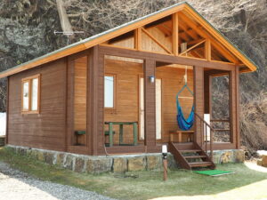 Außenansicht einer Holzhütte mit Veranda und Hängematte