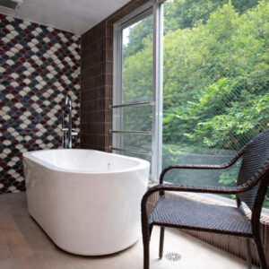 White soaking tub beside window with woven chair