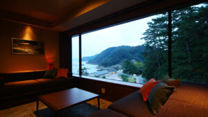 Zona soggiorno della camera davanti a una grande finestra con vista sulla costa