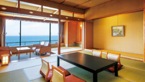 Camera in tatami con tavolo basso e sedie accanto alla finestra con vista sull’oceano