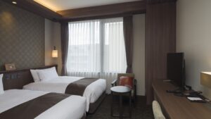 Twin beds beside window and desk in guest room