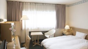 Bett neben einem kleinen Tisch und Stuhl am Fenster