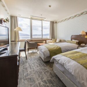 Zwei Einzelbetten im Gästezimmer mit Fenster und Stühlen