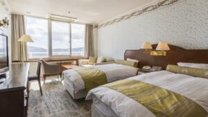 Zwei Einzelbetten im Gästezimmer mit Fenster und Stühlen