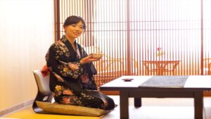 유카타를 입은 여성이 낮은 탁자에 앉아 있는 모습