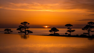 Sonnenuntergang über dem Ozean neben einem Infinity-Pool