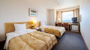Zwei Einzelbetten in einem Gästezimmer mit Schreibtisch am Fenster