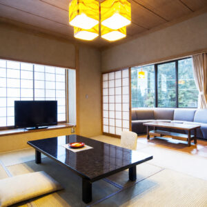 Camera in tatami con tavolo basso, cuscini e posti a sedere sul divano