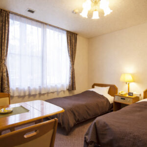 Letti singoli accanto a una finestra e a un tavolino