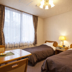 Letti singoli in una camera con tavolo e finestra