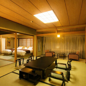 Camera in tatami con tavolo basso, sedie e letti
