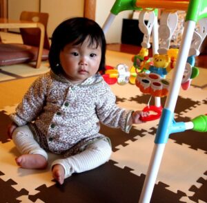 Child sitting on floor play mat with toy gym