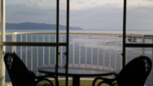 Vue sur l’océan à travers des portes coulissantes avec des chaises sur le balcon