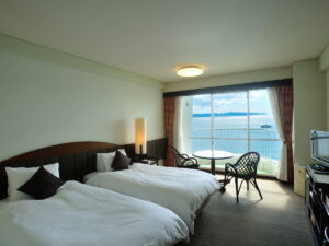 Lits jumeaux près de la fenêtre avec coin salon vue sur l’océan