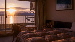 Beds beside a window overlooking the sea at sunset