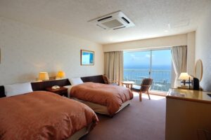 Twin beds in guest room facing ocean balcony