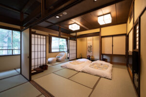 Habitación de tatami con futones tendidos y sillas junto a la ventana