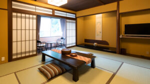 Habitación de tatami con mesa baja y sillas junto a la ventana