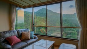 Ledersofa und Tisch neben großem Fenster mit Bergblick