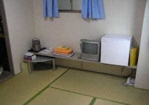 Coin d’une chambre en tatami avec bouilloire, télévision et petit réfrigérateur