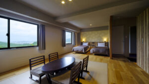 配有两张床、桌子和窗户的客房