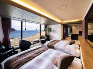 Twin beds in a room with ocean view windows.