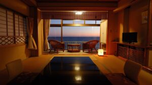 Vue sur l’océan depuis une chambre tatami avec des chaises près de la fenêtre