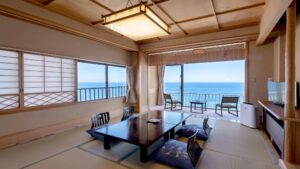 Chambre en tatami avec table basse et balcon avec vue sur l’océan