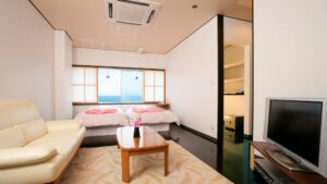 配有两张单人床、沙发、桌子和电视的客房