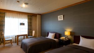 Twin beds beside window and desk in guest room