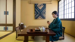Donna seduta a un tavolo basso in una stanza con tatami