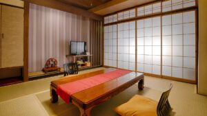 Tatami-Zimmer mit niedrigem Tisch, Bodensessel und Fernseher