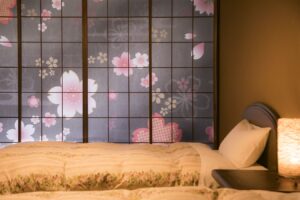 Zwei Einzelbetten neben floralen Shoji-Schirmen und einer Lampe