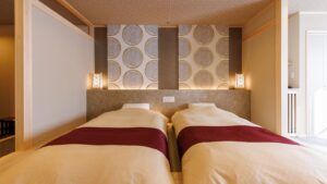 Zwei Betten mit gemusterter Wand hinter dem Kopfteil