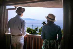 Zwei Personen blicken von einem Balkon auf das Meer