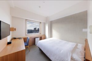 Cama individual junto al escritorio y la ventana en la habitación