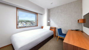 Cama individual junto al escritorio con vista por la ventana