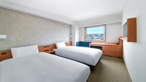 Camas individuales en una habitación con asientos junto a la ventana