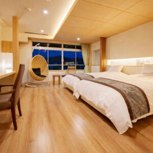 Camas individuales junto a una gran ventana y una silla colgante