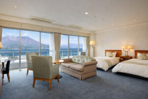 Guest room with two beds, sofa, chairs, and ocean view