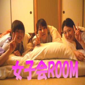 3人の女性が布団に寝転び、ピースサインをしている様子