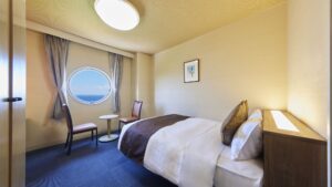 Lit à côté d’une fenêtre ronde avec deux chaises et une table
