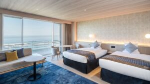 Lits jumeaux à côté d’un coin salon et d’une fenêtre face à l’océan