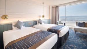 Lits jumeaux dans une chambre donnant sur un balcon face à l’océan