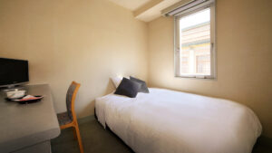 Letto singolo accanto alla scrivania e alla finestra nella camera