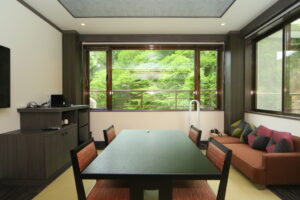 Zona de estar con mesa y sofá junto a grandes ventanales