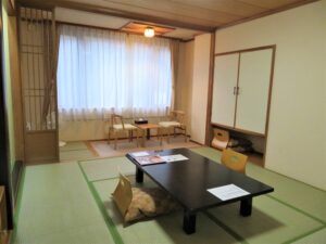 Habitación de tatami con mesa baja y sillas junto a la ventana