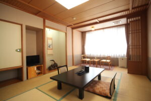 Habitación de tatami con mesa baja y sillas junto a la ventana