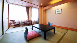 Habitación de tatami con mesa baja y sillas junto a la ventana