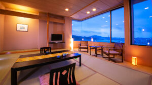 Habitación de tatami con mesa baja, sillas y grandes ventanales